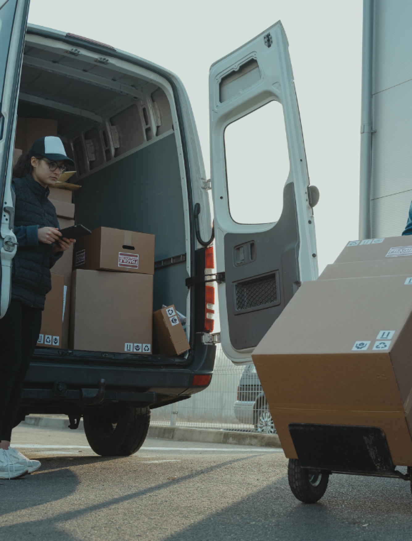 Professionele verhuisservice voor particuliere woning Vrouw tekent documenten bij een bestelbus met dozen, terwijl een verhuizer helpt bij het verplaatsen van spullen naar een woning.